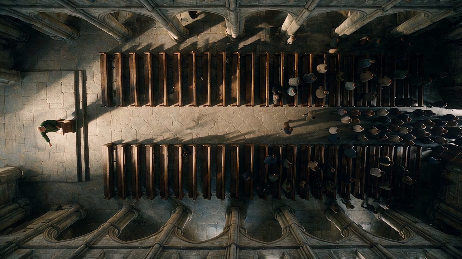 Overhead shot of a cathedral nave, a figure in the aisle between the pews.