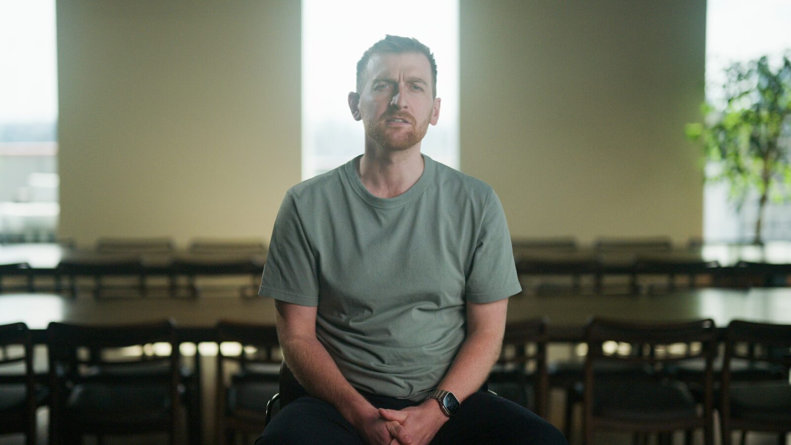 A founder in a grey t-shirt, seated in an empty meeting room.